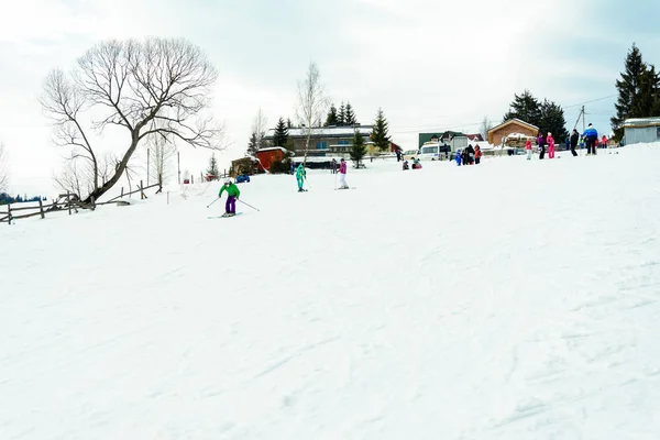 Yablunivka, ukraine februar 2019: Ein Mann in grüner Jacke geht im Karpatendorf auf dem Berg koryvka Skifahren. — Stockfoto