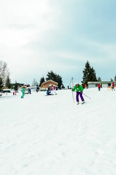 Yablunivka, ukraine februar 2019: Ein Mann in grüner Jacke mit Helm und Brille geht im Karpatendorf auf dem Berg Koryvka Skifahren. — Stockfoto