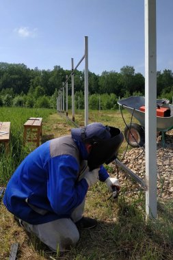 Kaynakçı hous etrafında çit için yeni bir metal çerçeve kaynak