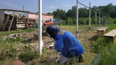 Bir çit montajcı yeni bir çit sonrası bir metal profil kaynak.