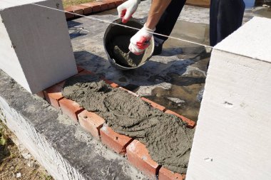 İşçi beyaz gaz blokları duvar inşaat ilk satırı başlar.