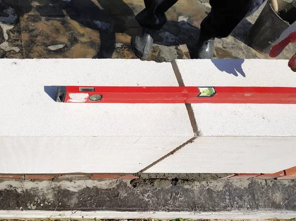 El maestro utiliza el nivel en la construcción y mampostería de la casa en el campo . — Foto de Stock