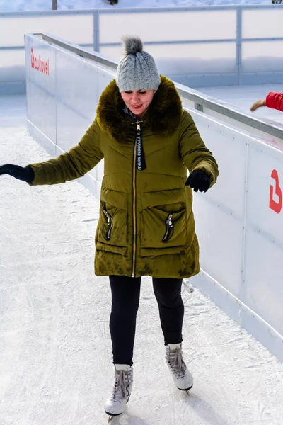 Bukovel, Ucrânia 12 de fevereiro de 2019 - menina de jaqueta verde patina no gelo . — Fotografia de Stock