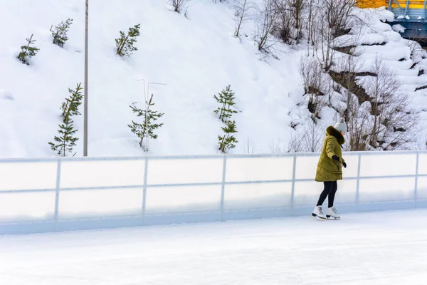 Bukovel, Ukraine 12. Februar 2019 - Mädchen in grüner Jacke Schlittschuhe auf dem Eis. — Stockfoto