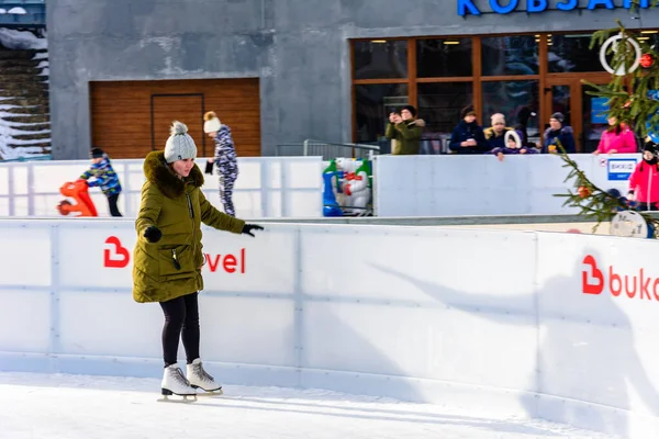 Bukovel, Ukraine 12. Februar 2019 - Mädchen in grüner Jacke Schlittschuhe auf dem Eis. — Stockfoto