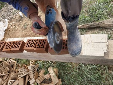 Kırsal bir bahçede bir açı öğütücü ile tuğla kesme.