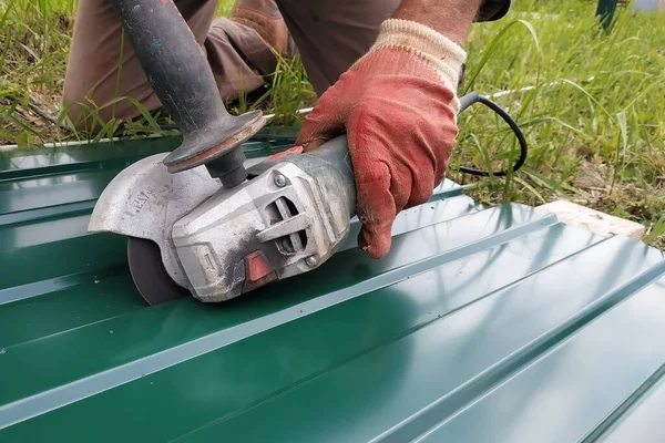 Çatı çalışmaları sırasında, bir inşaat işçisi bir açı öğütücü ile yamuk profili ile çelik bir levha spreyler. — Stok fotoğraf