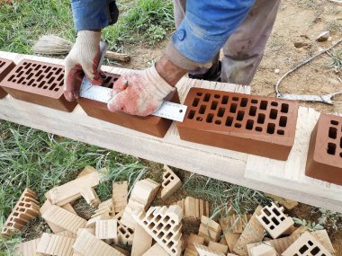 İşçi inşaat için daha fazla ölçüm ve kırpma için cephe tuğla çevirir.