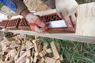 İşçi inşaat için daha fazla ölçüm ve kırpma için cephe tuğla çevirir.