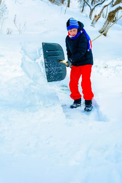 Limpeza de neve no inverno, o menino pás neve . — Fotografia de Stock