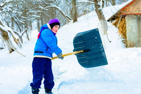 Depois de neve pesada, o menino limpa a neve com uma pá . — Fotografia de Stock