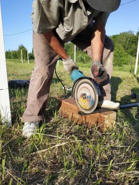 Bir açı değirmeni işçisi dışında bir metal profil keser.