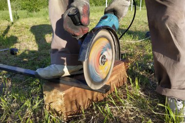 Bir açı değirmeni işçisi dışında bir metal profil keser.