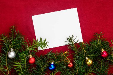 Noel ağacı ve Noel topları dalları ile kırmızı bir arka plan üzerinde Noel dilekleri için kağıt parçası.