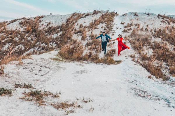 Vackra par promenader i fosfat-gips vita bergen i Ukraina, flickan i en röd klänning. — Stockfoto