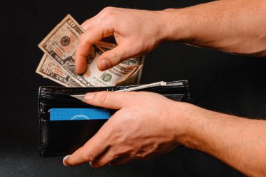 Deri cüzdan, üzerinde para olan siyah arka plan 2020 'de erkeklerin elinde.