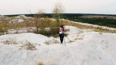 Üç ayaklı bir kamerayla manzara fotoğrafçısı beyaz dağlardaki yeşil bir yapay gölün fotoğrafını çekiyor. Fosfor-alçıtaşı yığını. Hava 4k videosu