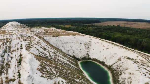 白い山の中で緑の人工湖の空中4kビデオ。ウクライナの産業廃棄物からリン酸石膏のヒープ. — ストック動画
