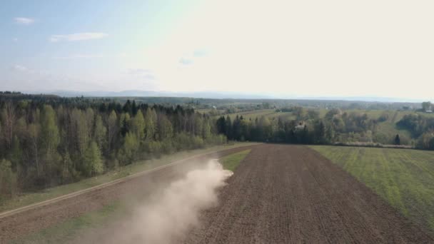 Zemědělec obdělává pole na pásovém traktoru a uvolňuje půdu pomocí kultivátoru kotoučů na pozadí lesa a modré oblohy. Záběry 4k. — Stock video