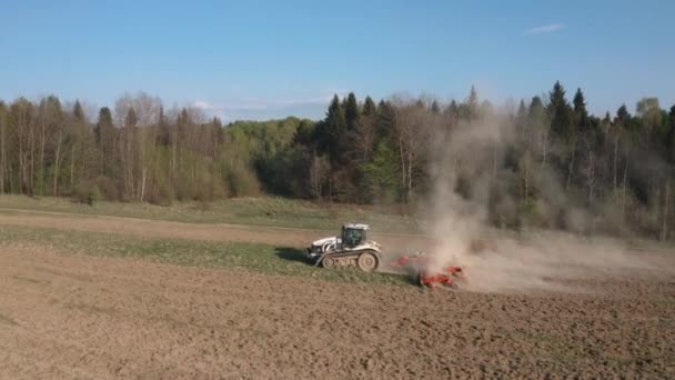 Zijaanzicht van een vliegtuig dat over een veld vliegt dat door een rupstrekker wordt geteeld tijdens een crisis in de agro-industriële sector — Stockvideo