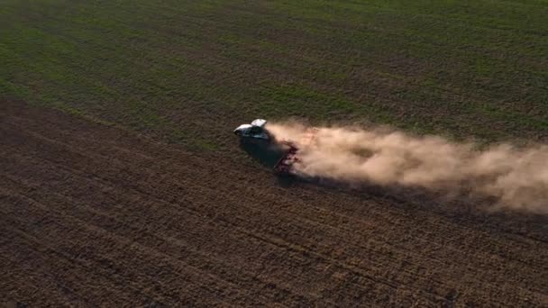 Un tracteur sur chenilles cultive le sol dans un champ agricole. Vue de dessus volant sur un drone. Angle diagonal en vidéo 4k . — Video