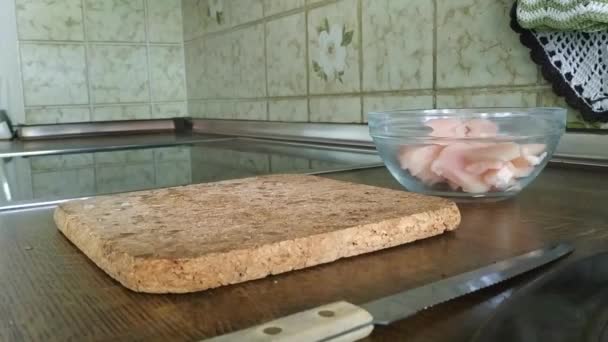 Tânăra taie filet de pui în bucătărie cu un cuțit de bucătărie. Gătitul mâncărurilor de carne la domiciliu . — Videoclip de stoc