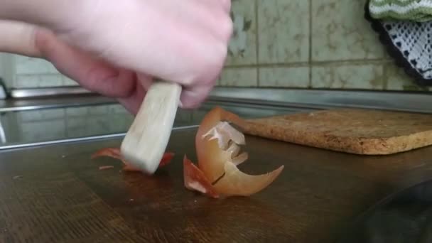 Ibu muda memotong bawang di papan kayu dekat. Nyonya rumah membersihkan bawang dengan pisau meja.. — Stok Video