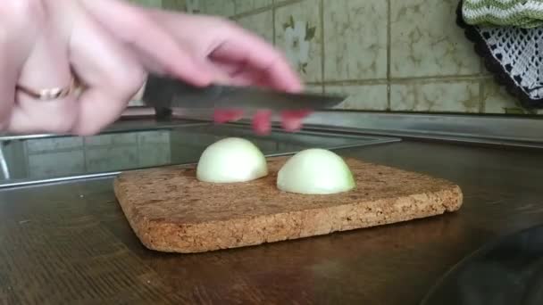 Młoda matka kroi cebulę na drewnianej desce z bliska — Wideo stockowe