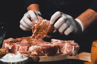 Kebap ve jambon pişirmek için marine edilmiş çiğ domuz eti. Restoranın eldivenli şefi 2021 baharatlı fesleğen ve baharatlı ete iyi davranır..