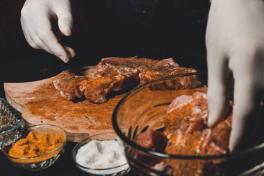 Kebap ve jambon pişirmek için marine edilmiş çiğ domuz eti. Restoranın eldivenli şefi 2021 baharatlı fesleğen ve baharatlı ete iyi davranır..