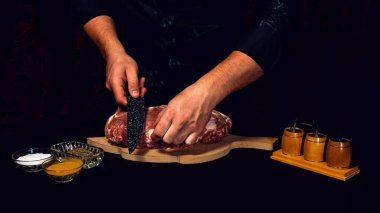 Restoranın koyu renk üniformalı şefi eti siyah bir mutfak bıçağıyla keser. Salamura edilmiş domuz bifteği siparişi. Çok fazla yağ kesiyorum..