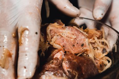 Eldivenli şef Gürcistan 'da kebap pişirmek için tabakta et yoğurur. 2021 'in karanlık arka planında rendelenmiş patates ve soğanlı domuz salamurası..