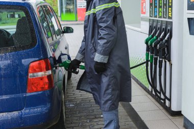 Ukrayna 'daki bir benzin istasyonunda çalışan bir çalışan, sürücünün arabaya benzin ya da dizel yakıt doldurmasına yardım eder. Bir benzin istasyonu çalışanı bir araba tankına benzin tabancası yerleştirir. Dolyna, Ukrayna - 12 Mayıs 2020.