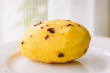 Büyük, soyulmuş yeni patatesler, tahtadan yapılmış sarı patatesler. Patatesler zarar görmüş ve bozulmuş..
