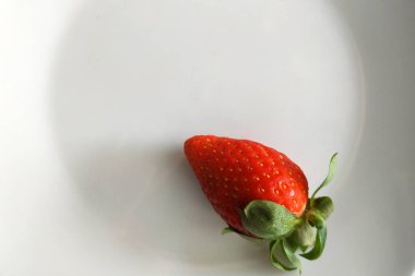 Sadece bir tabakta sulu çilekler, fırın ürünleri için favori bir meyve, lezzetli bir tatlı, yeşil yapraklı kokulu bir çilek..