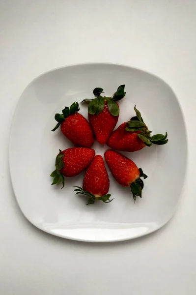 Fraises sur une assiette blanche bordée d'un cercle, vue de dessus, fruits juteux et très utiles pour le petit déjeuner. — Photo