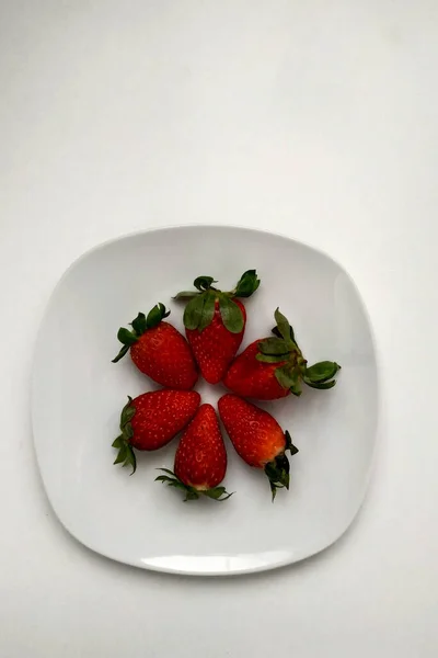 Stroberi pada piring putih dilapisi dengan lingkaran, pemandangan puncak, buah yang berair dan sangat berguna untuk sarapan. — Stok Foto
