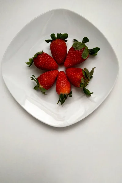 Клубника на белой тарелке с кругом, вид сверху, сочные и очень полезные фрукты на завтрак. — стоковое фото