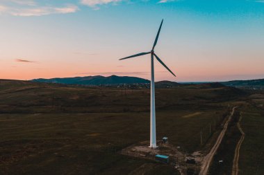 Rüzgar türbini, alternatif enerji, rüzgar enerjisi, dağlardaki bir tarlada bir rüzgar değirmeni, günbatımında bir rüzgar türbininin üst görüntüsü. 2021