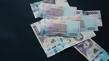 Ukrayna hrivnisi bin tane hryvniaya düşer, kara arka planda uçar, Ukrayna devleti parası, bir sürü fatura..