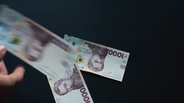 Banknotlar binlerce hryvnianın yüzey değeri, para uçar, siyah bir yüzeye düşer, yeni Hryvnia mezhepleri. — Stok video