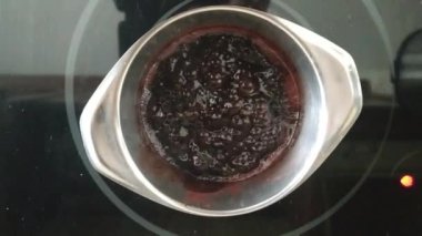 Ev sahibi mutfakta tereyağlı kakao pişirir. Sıcak çikolata kaynatırken kabarcıklı harika bir doku..
