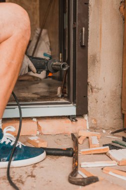 Usta metal bir kapı kutusuna el matkabıyla delikler açıyor, yakın plan, yeni kapılar takılıyor. 2020