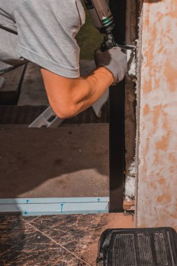 İşçi kapıyı köpükler ve yalıtır, marangoz sünger tabancası kullanır, çalışma sürecine yakın çekim. 2020
