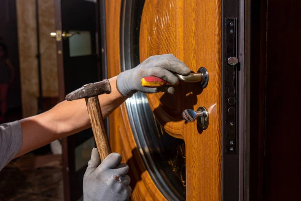 The master worker installs a door lock in the front door, metal doors with a polymer coating.2020