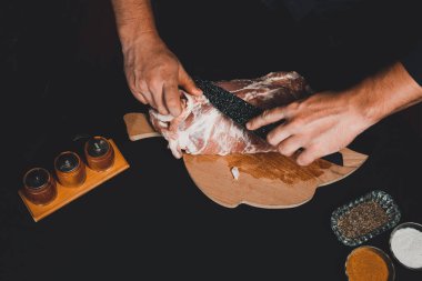 Adam domuz şişi hazırlıyor, büyük bir mutfak bıçağıyla fazla domuz yağı kesiyor. 2020