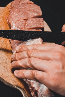 Tahta üzerinde bir adam domuz etini büyük parçalara ayırır, yakın plan barbeküde domuz boynu nasıl kesilir gösterir. 2020