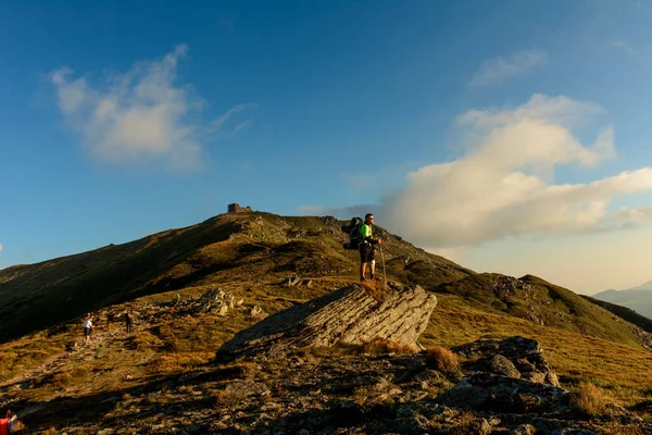 山の頂上から若い男が降りますピップ イワン 山の周りの壮大な風景を観察します 大きなハイキングバックパックを運びます 2020 — ストック写真