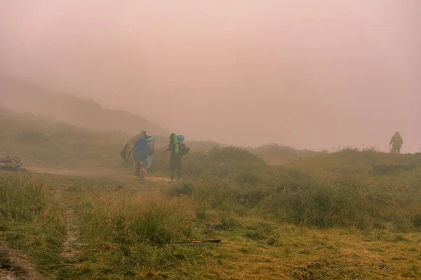 Mountain lake, tourists near a mountain lake, rain in the mountains, tourists in raincoats, fog near the lake in the Carpathians, the highest lake in the Carpathians of Ukraine Brebeneskul.2020