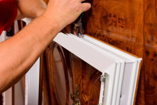 Bir işçi eve yeni plastik pencereler takıyor, pencereye elle açılan bir elektrikli matkapla delikler açıyor. 2020